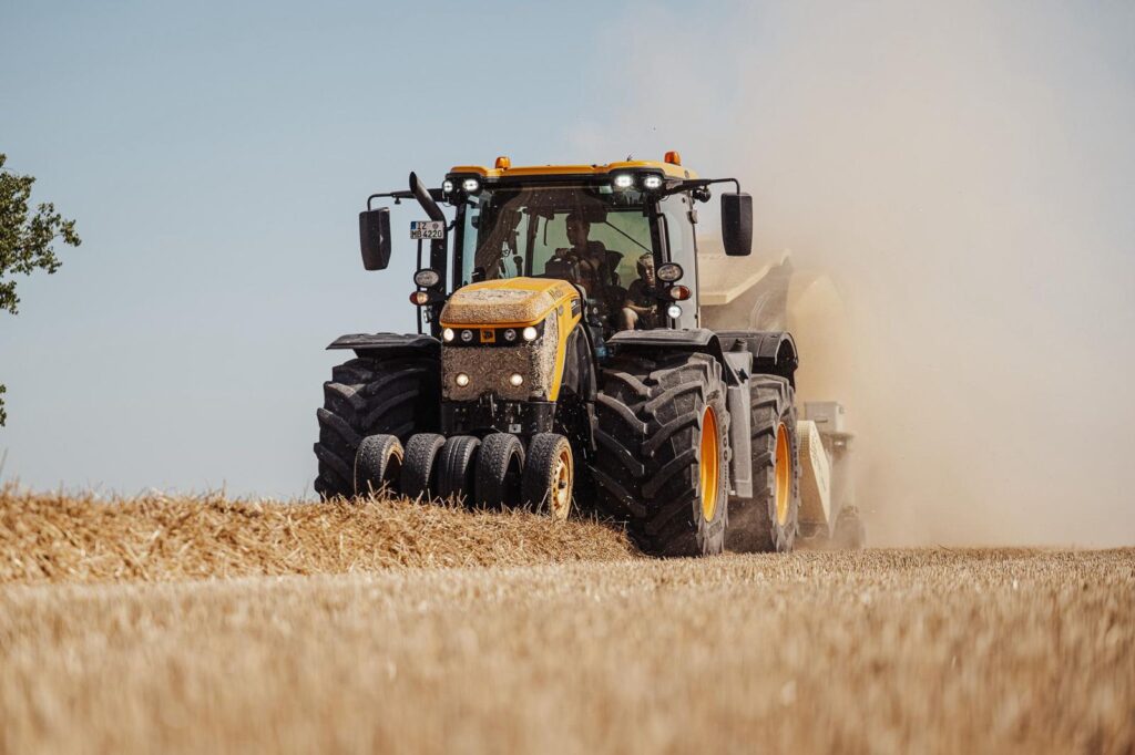 Gelber Traktor auf einem Getreidefeld mit einer Maschine angehängt