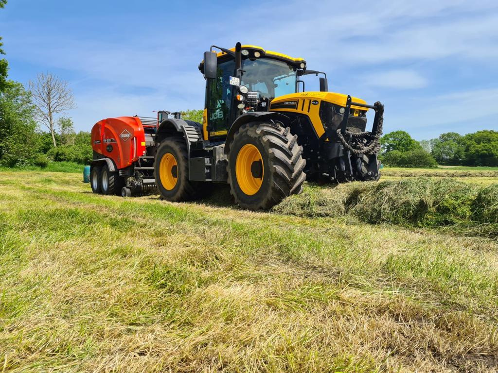 Gelber Traktor auf dem Feld bei der Heuernte
